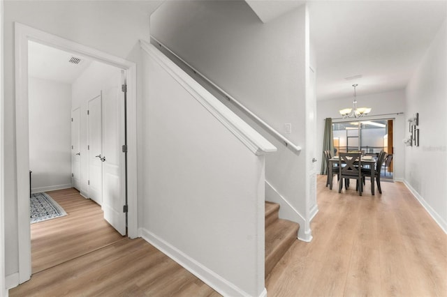 staircase with a chandelier and wood-type flooring