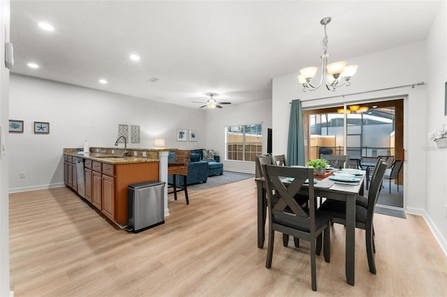 dining room featuring ceiling fan with notable chandelier, light hardwood / wood-style floors, and sink