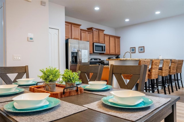 kitchen with a kitchen bar, sink, appliances with stainless steel finishes, and light hardwood / wood-style flooring