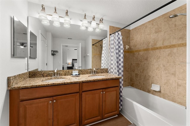 bathroom with ceiling fan, shower / bath combo with shower curtain, vanity, and a textured ceiling