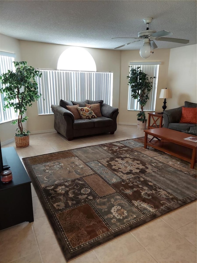 tiled living room with ceiling fan and a textured ceiling