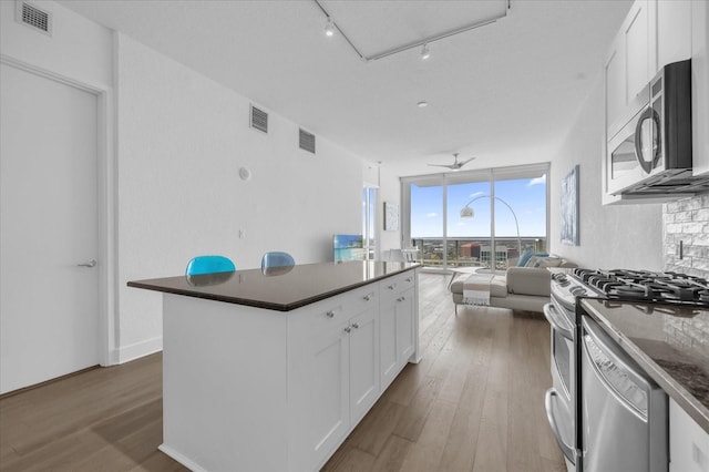 kitchen with white cabinets, stainless steel appliances, ceiling fan, and wood-type flooring