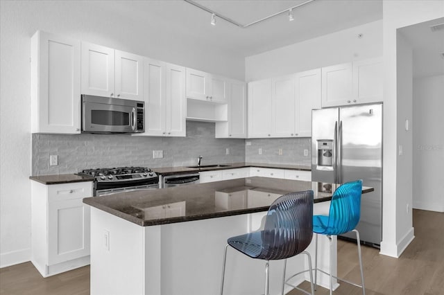 kitchen featuring a kitchen island, stainless steel appliances, a kitchen breakfast bar, and white cabinetry