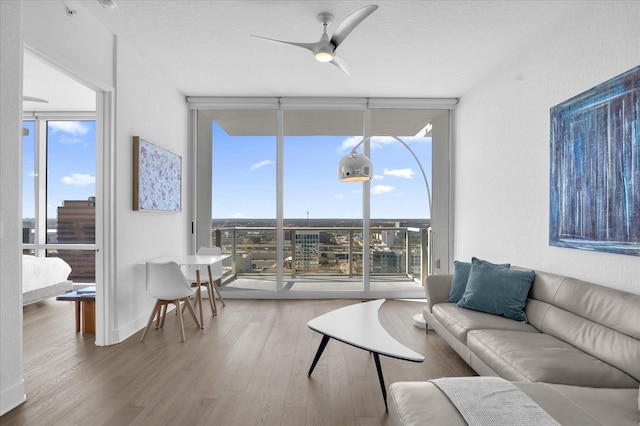 living room with hardwood / wood-style flooring, ceiling fan, a wealth of natural light, and expansive windows