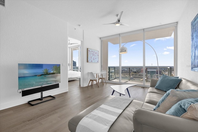 living room with wood-type flooring, ceiling fan, and floor to ceiling windows