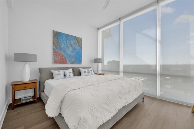 bedroom featuring wood-type flooring, ceiling fan, and expansive windows