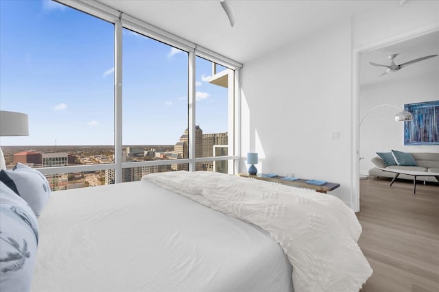 bedroom with light wood-type flooring, ceiling fan, and expansive windows