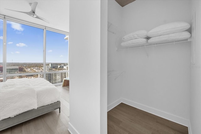 bedroom with hardwood / wood-style floors, ceiling fan, and a wall of windows