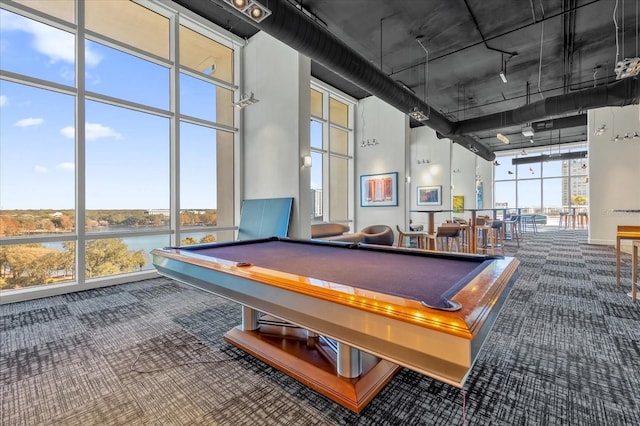 recreation room featuring a towering ceiling, pool table, floor to ceiling windows, and a water view