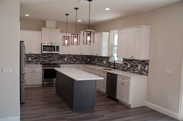 kitchen with pendant lighting, sink, appliances with stainless steel finishes, white cabinetry, and a kitchen island