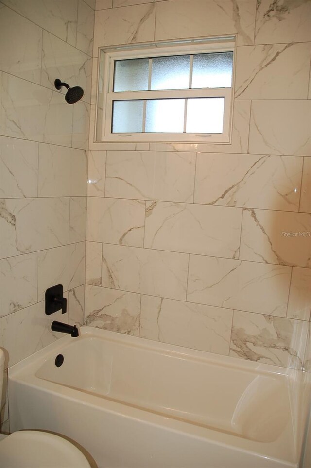 bathroom with toilet and tiled shower / bath