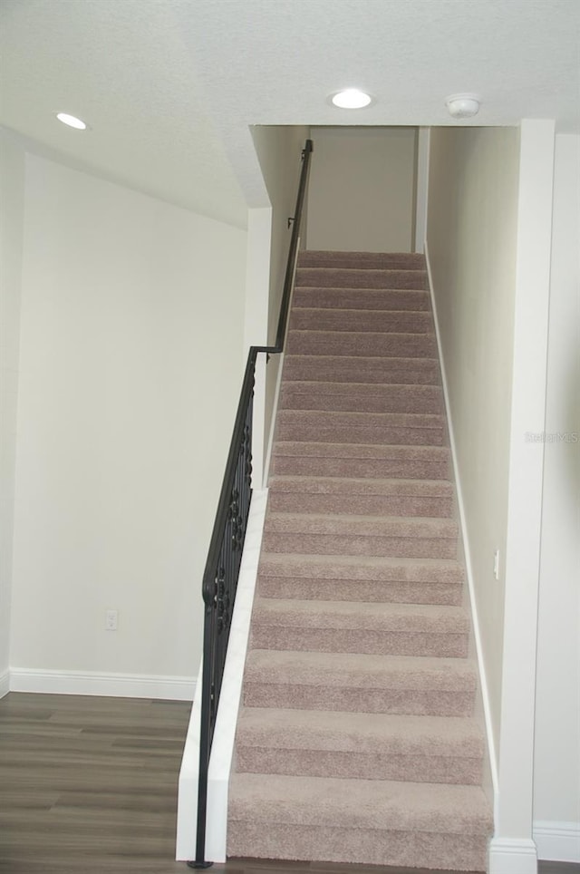 stairs featuring hardwood / wood-style flooring and a textured ceiling