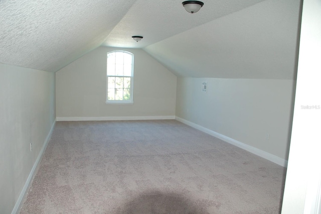 bonus room with vaulted ceiling, light colored carpet, and a textured ceiling