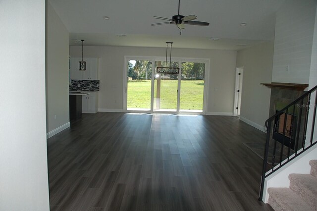 unfurnished living room with dark wood-type flooring and ceiling fan