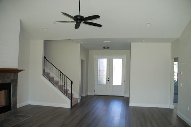 entrance foyer featuring a tiled fireplace, dark wood-type flooring, ceiling fan, and french doors