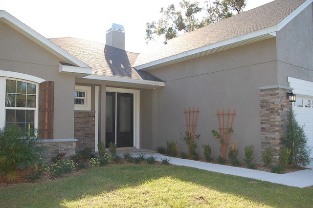 view of exterior entry with a garage and a yard