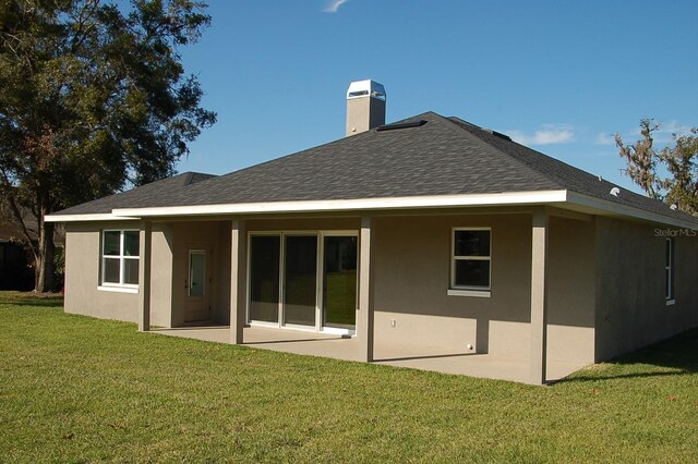 rear view of property with a lawn and a patio