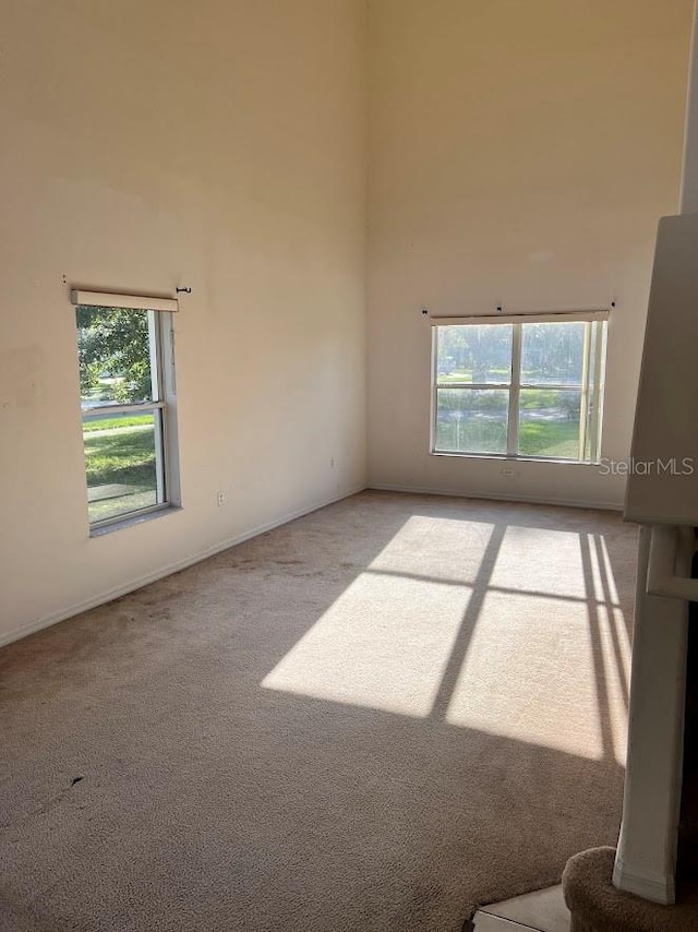 carpeted empty room featuring a high ceiling