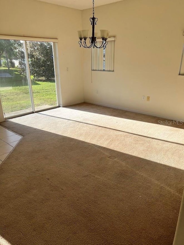 unfurnished dining area featuring carpet floors and a chandelier