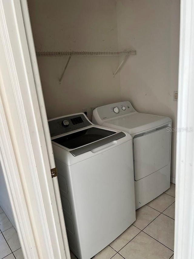 laundry area with washer and clothes dryer and light tile patterned floors