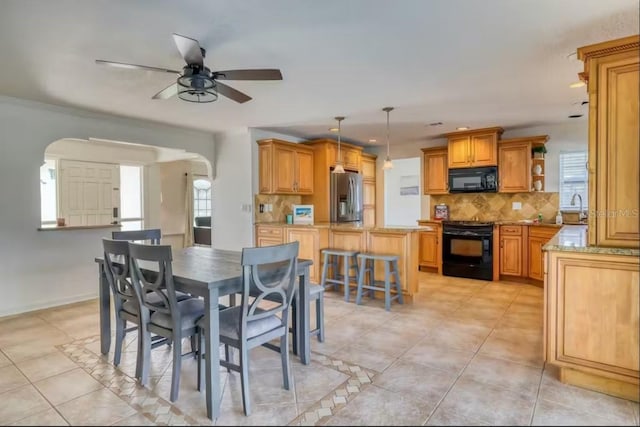 tiled dining space featuring ceiling fan and sink