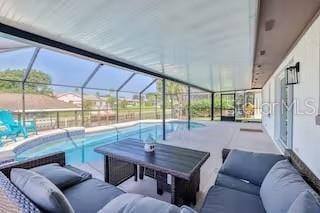 view of pool with a lanai, a patio area, and an outdoor living space