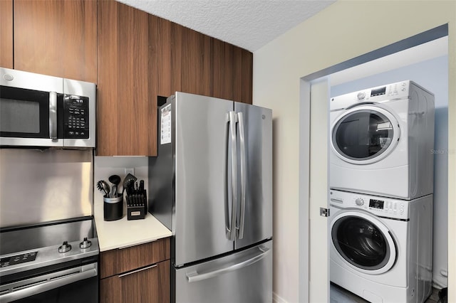 kitchen with a textured ceiling, stacked washer / drying machine, and appliances with stainless steel finishes