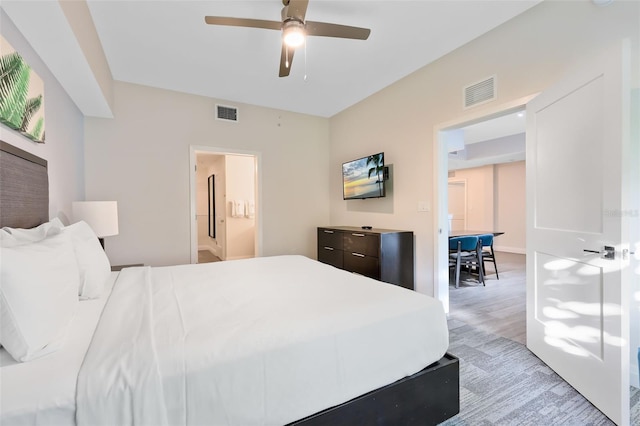 bedroom featuring ceiling fan, visible vents, light wood-style floors, and ensuite bath