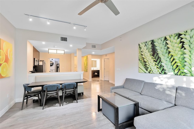 living area featuring visible vents, light wood-style flooring, baseboards, and a ceiling fan