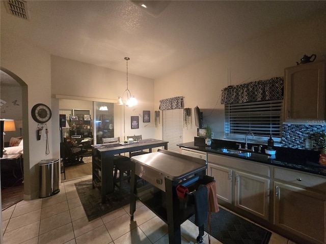 kitchen featuring sink, hanging light fixtures, a textured ceiling, light tile patterned flooring, and a chandelier