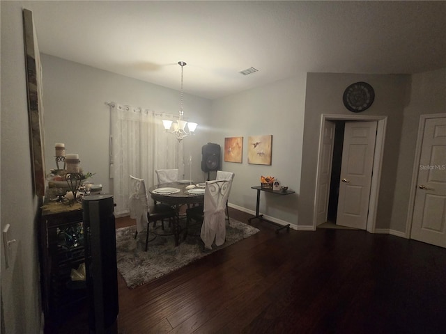 dining space with dark hardwood / wood-style floors and an inviting chandelier