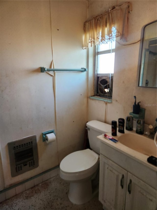 bathroom featuring vanity, heating unit, and toilet