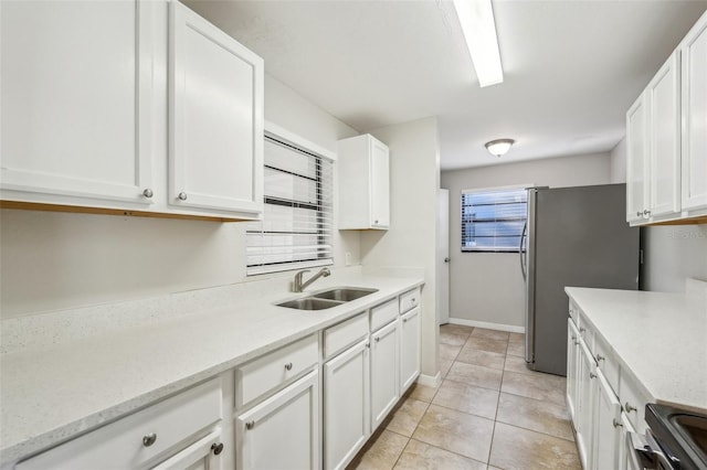 kitchen with sink, white cabinets, stove, and light tile patterned flooring