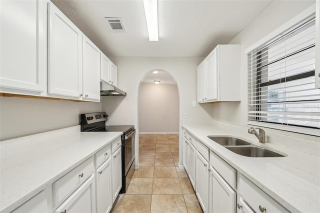 kitchen featuring light tile patterned floors, white cabinetry, electric stove, light stone counters, and sink