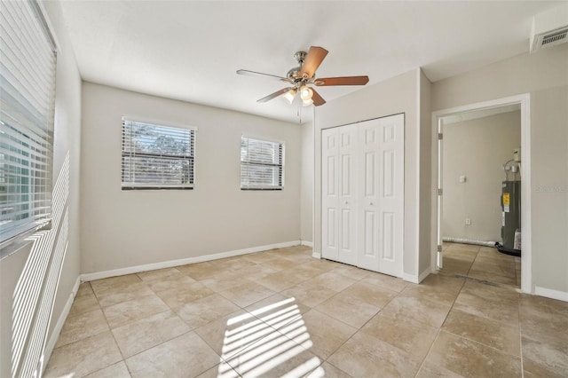 unfurnished bedroom featuring ceiling fan, a closet, and electric water heater