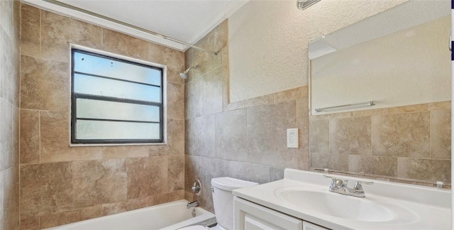 full bathroom featuring toilet, tiled shower / bath combo, vanity, and tile walls