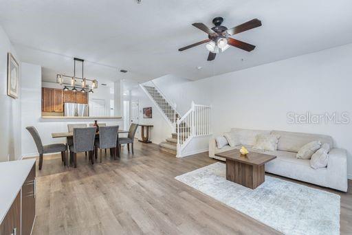 living room with wood-type flooring and ceiling fan with notable chandelier