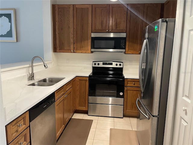 kitchen with light stone counters, sink, light tile patterned floors, and appliances with stainless steel finishes