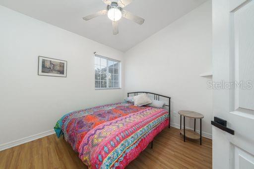 bedroom featuring ceiling fan, lofted ceiling, and wood-type flooring