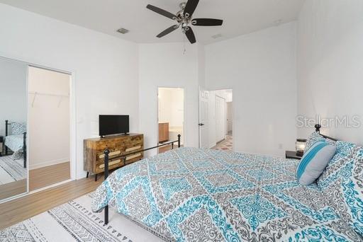 bedroom featuring ceiling fan, a towering ceiling, and light hardwood / wood-style floors