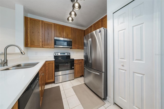 kitchen featuring light tile patterned flooring, appliances with stainless steel finishes, sink, and a textured ceiling