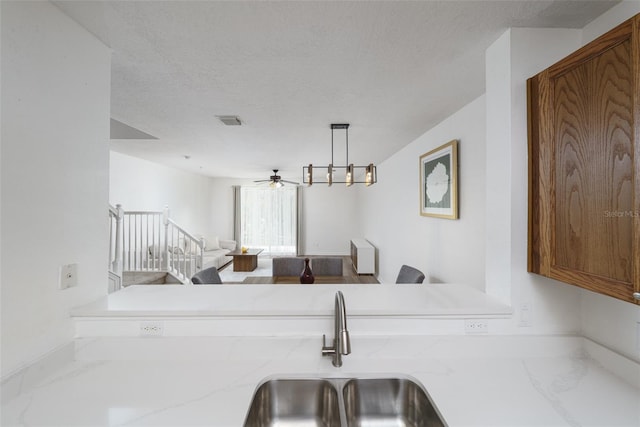 kitchen featuring hanging light fixtures, sink, a textured ceiling, and ceiling fan