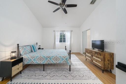 bedroom featuring hardwood / wood-style floors, vaulted ceiling, and ceiling fan