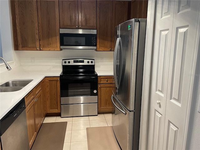 kitchen with appliances with stainless steel finishes, sink, and light tile patterned floors