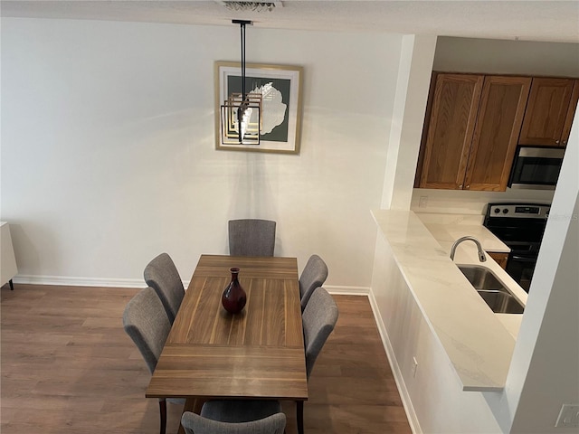 dining area with a notable chandelier, dark wood-type flooring, and sink