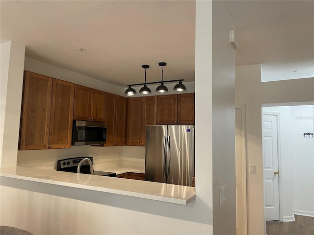 kitchen featuring stainless steel appliances, hanging light fixtures, and kitchen peninsula