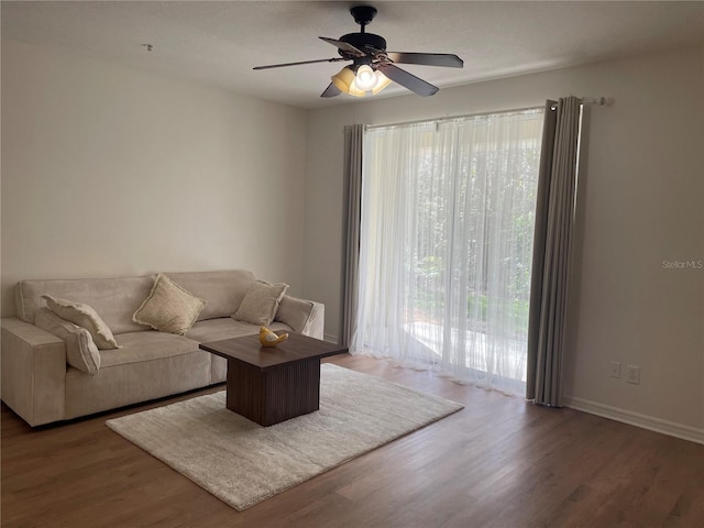 living room with dark wood-type flooring and ceiling fan