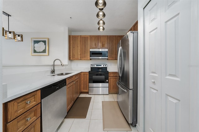 kitchen with sink, light tile patterned floors, hanging light fixtures, stainless steel appliances, and light stone counters