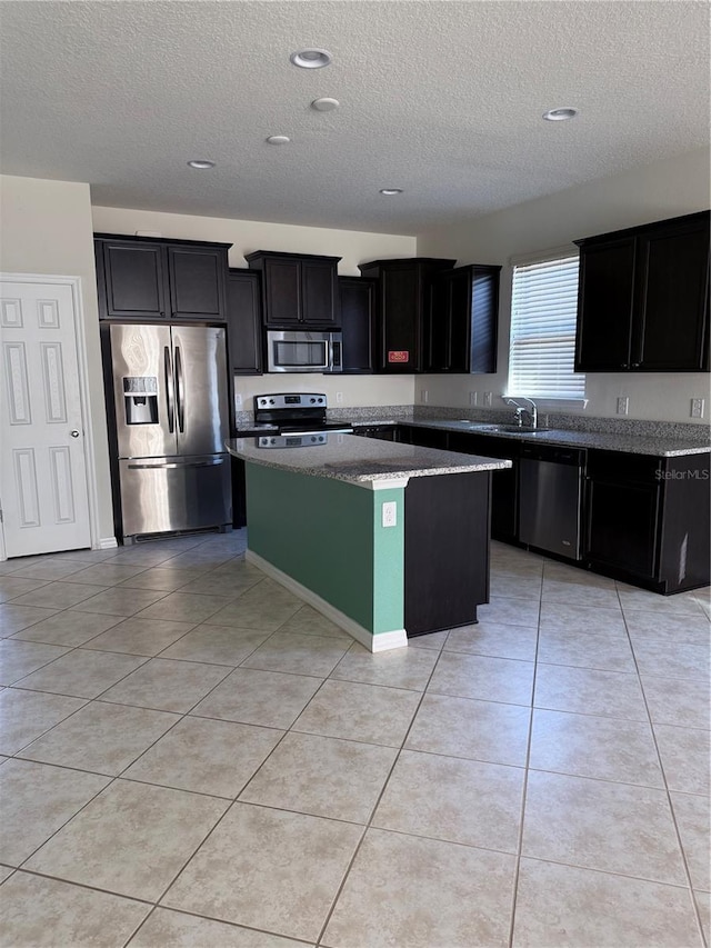 kitchen featuring light tile patterned floors, a kitchen island, stainless steel appliances, and a textured ceiling