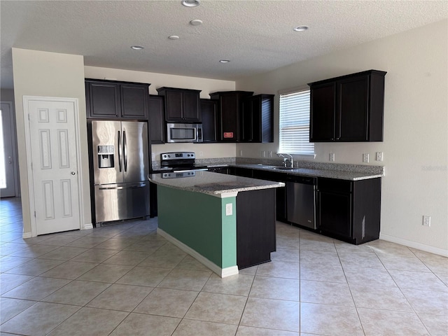 kitchen featuring sink, light tile patterned floors, a textured ceiling, appliances with stainless steel finishes, and a kitchen island